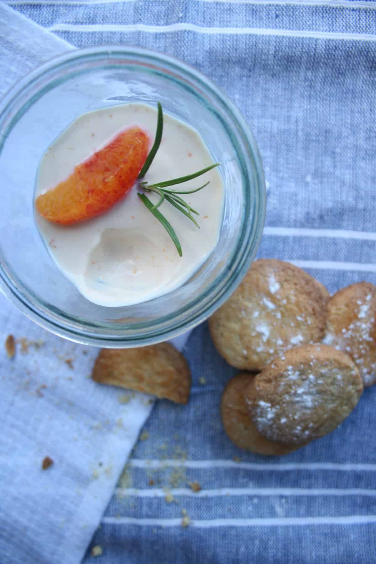 A close up of orange posset with rosemary biscuits to the side. 