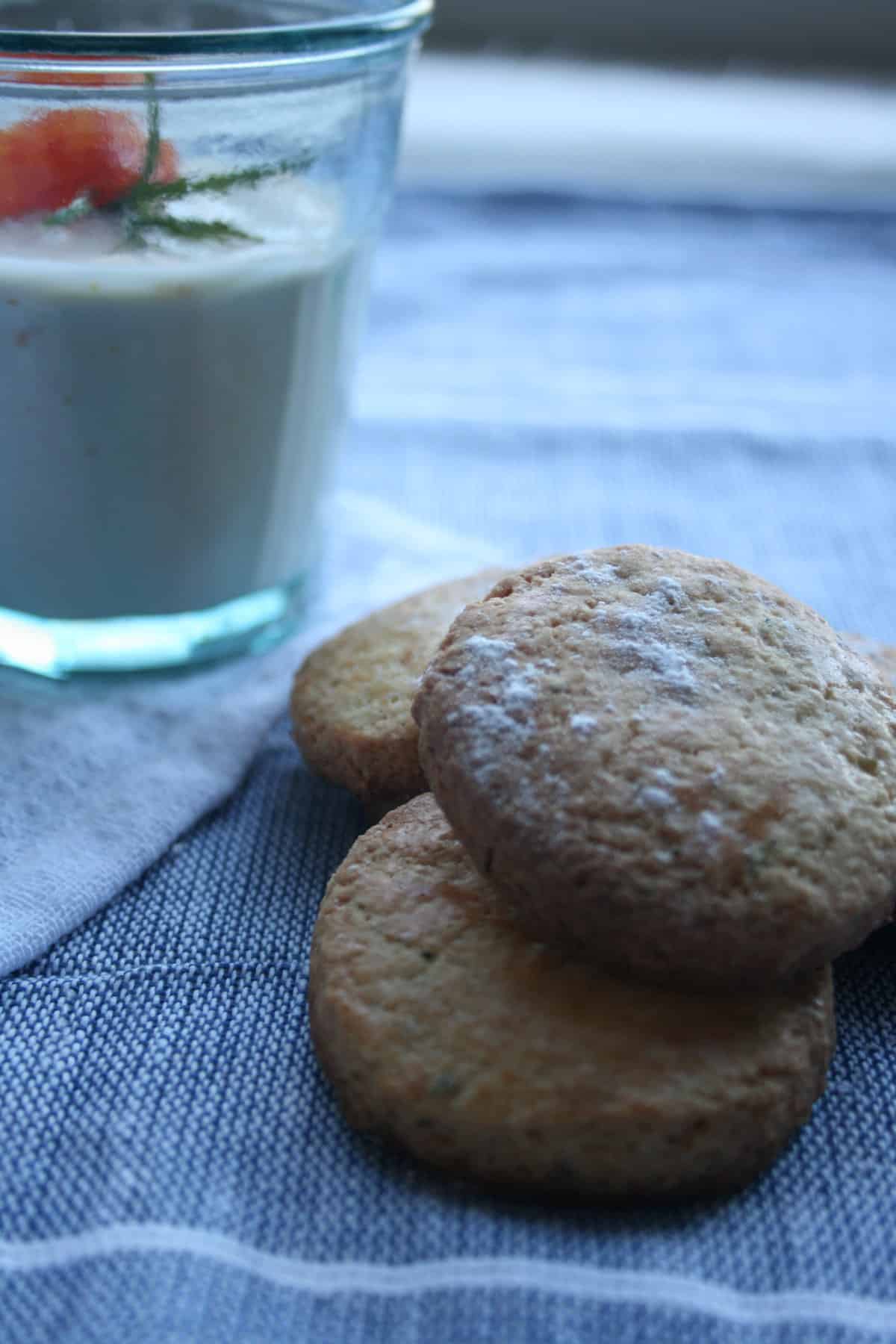 A pile of cookies with orange posset glass in the background.