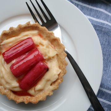A plate with rhubarb custard tart on top with a fork and napkin underneath.