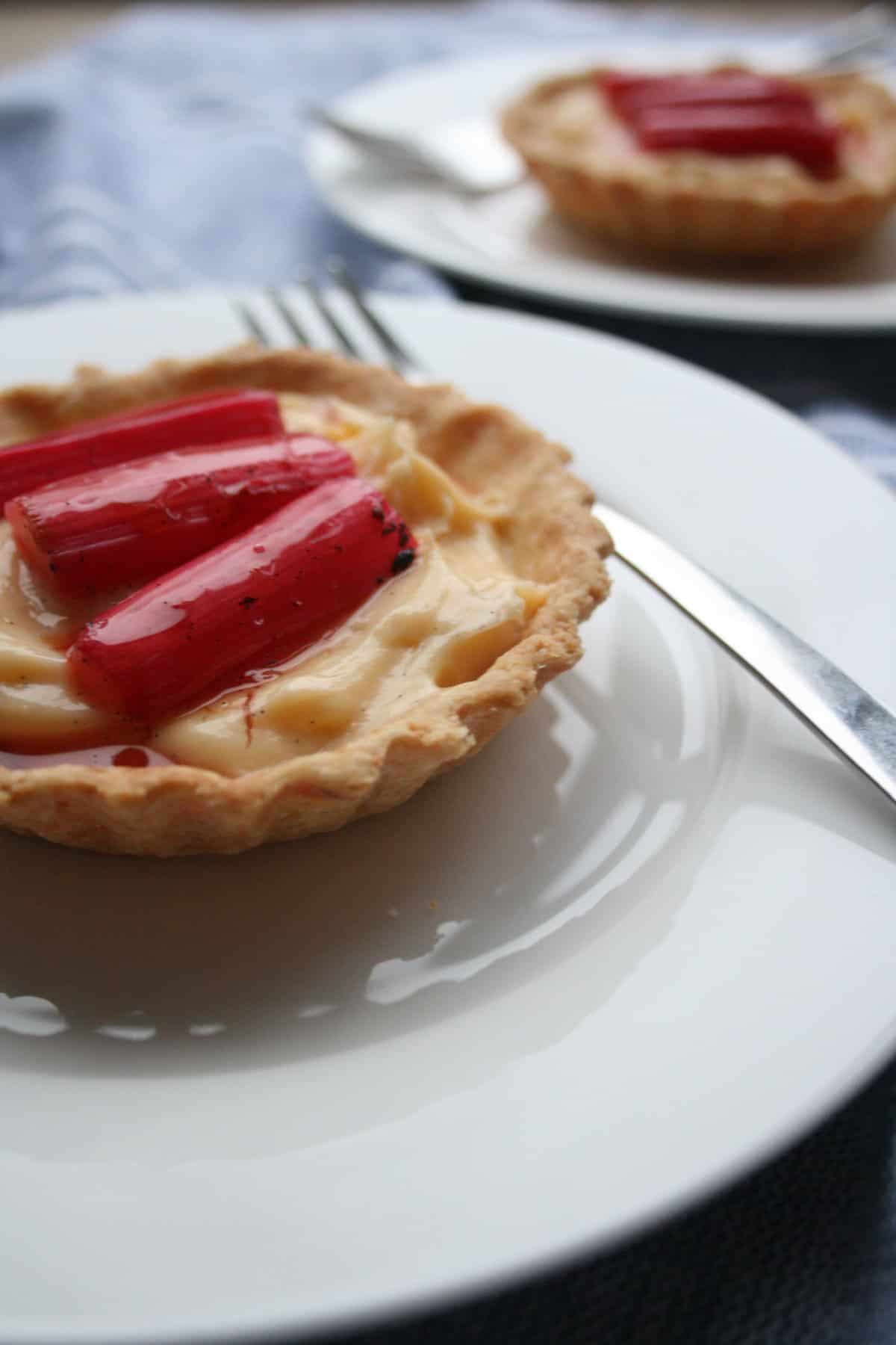 A plate with rhubarb and custard tart and fork.