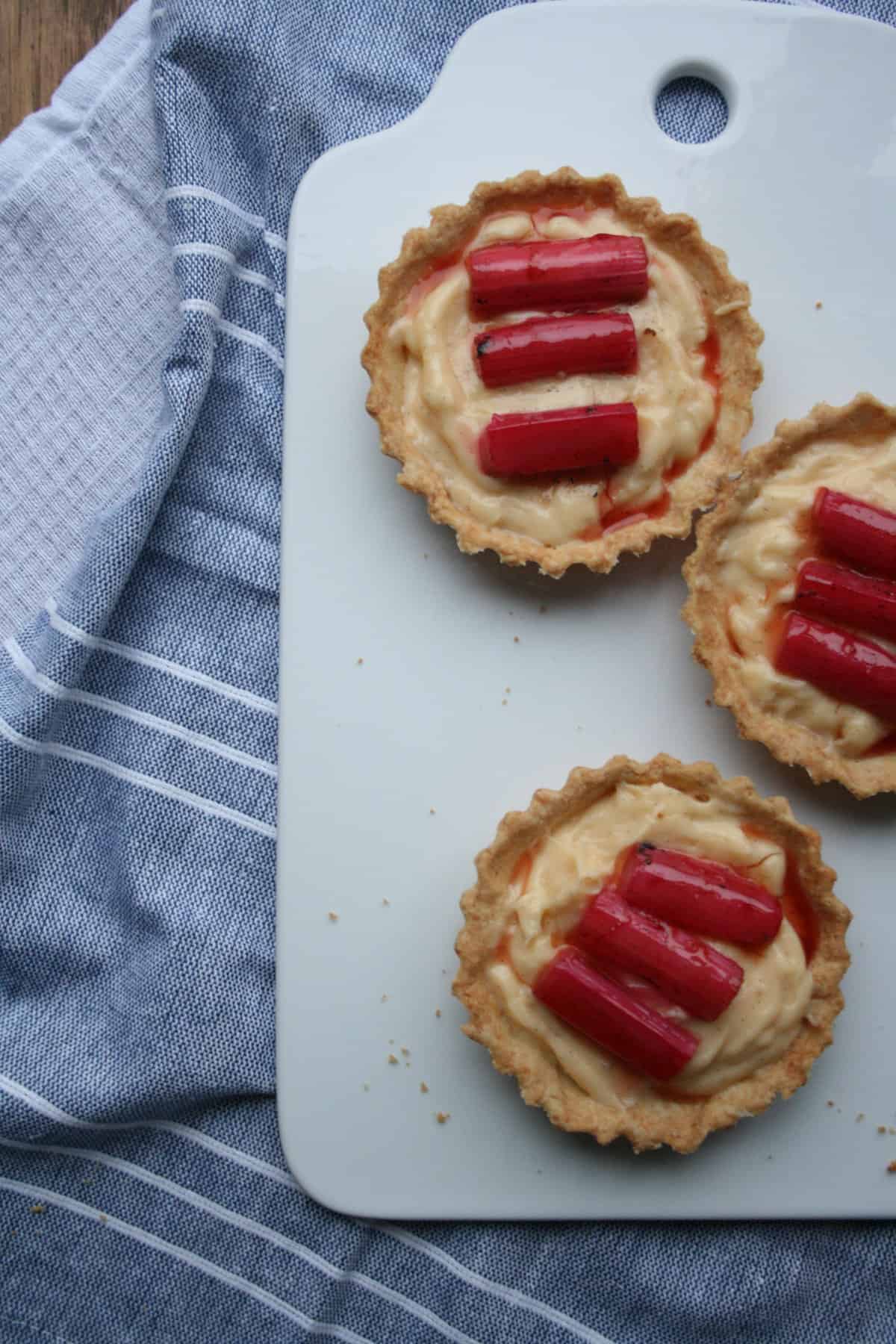 A board with three rhubarb and custard tarts on top. 