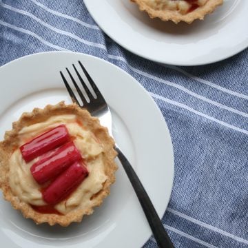 A pastry cup with custard and rhubarb on top with a fork.