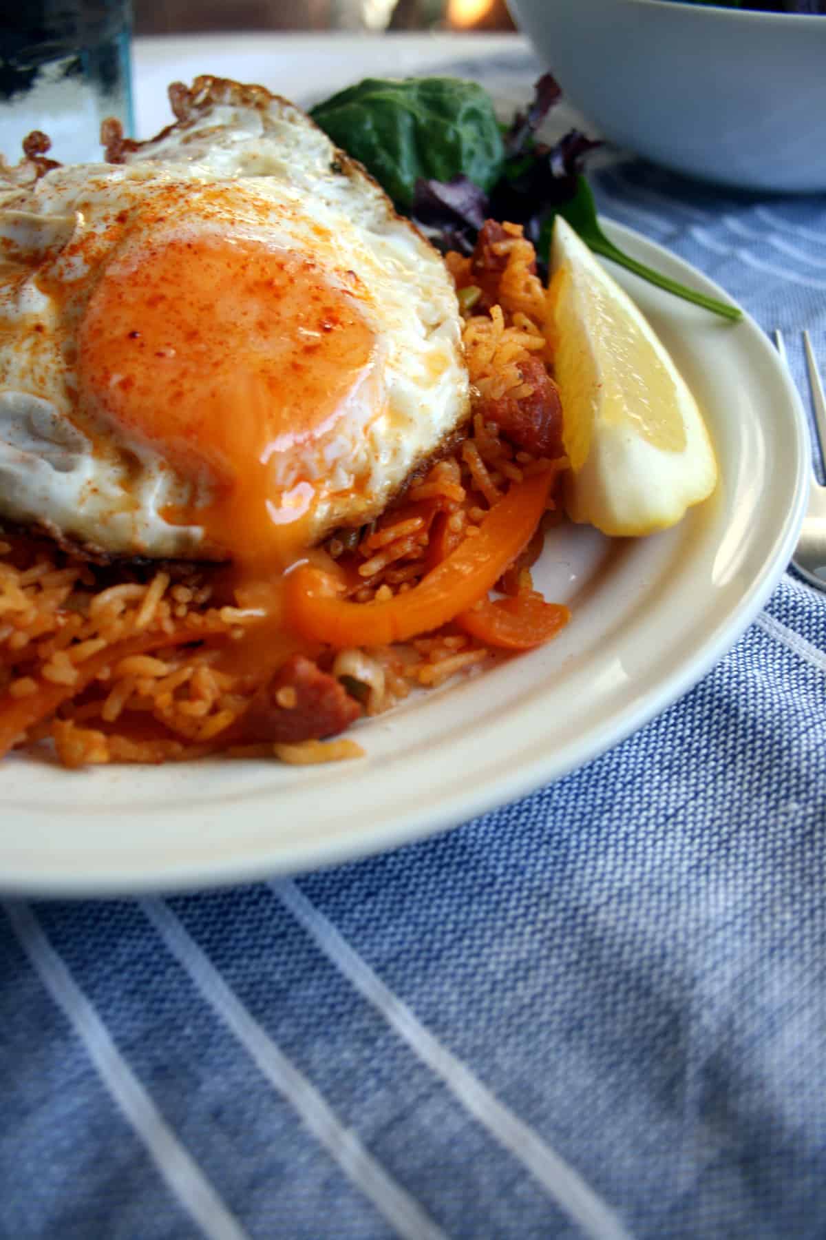 A plate with paella with an oozy fried egg yolk on top.