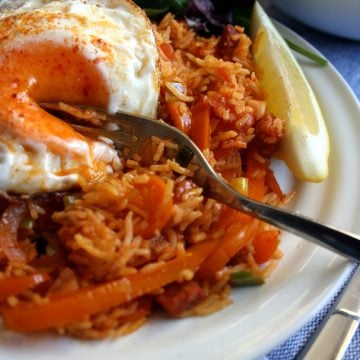 A plate with paella and an egg cut open with a fork.