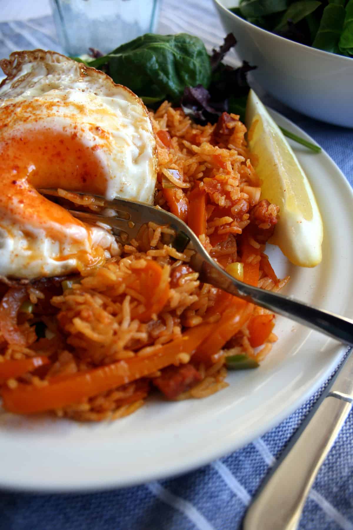 A plate with paella and an egg cut open with a fork.