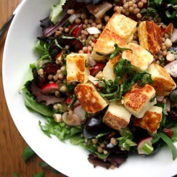 A halloumi cherry maftoul salad in a white bowl.