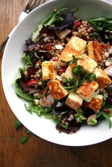 A halloumi cherry maftoul salad in a white bowl.