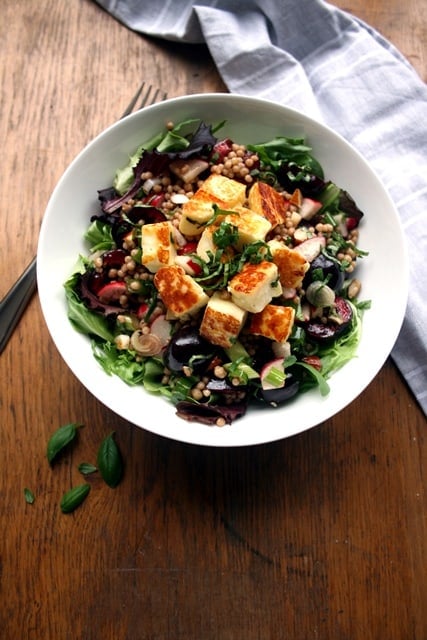 A bowl of halloumi cherry maftoul salad.