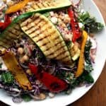A plate with chargrilled vegetables on top of a quinoa kale salad.
