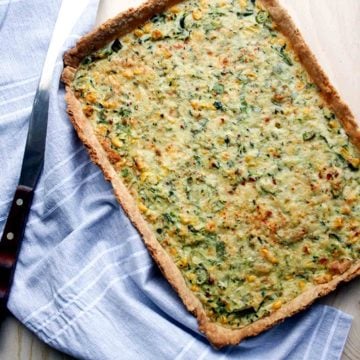 A courgette and corn tart with a napkin and spatula to the side.