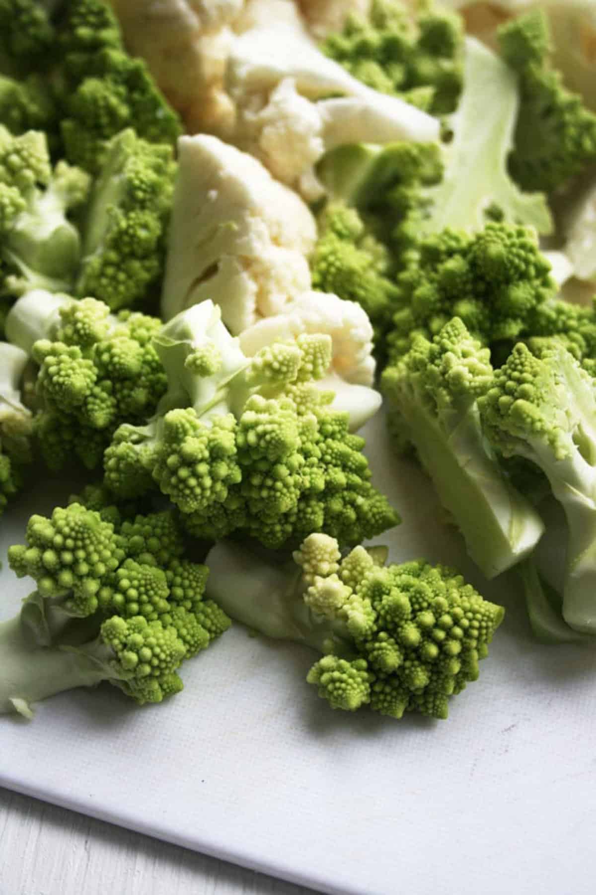 An array of romanesco and white cauliflower cut up.