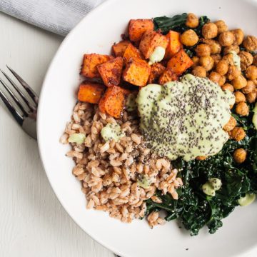 A plate of grains, greens, roasted swede and chickpeas with a green sauce and fork.