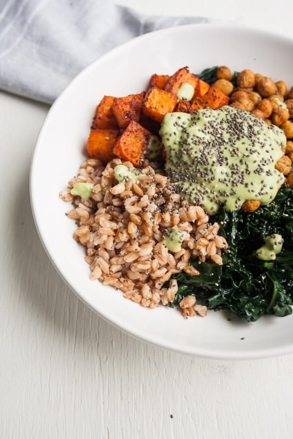 A plate with farro, roasted swede, chickpeas and greens with an avocado sauce on top.