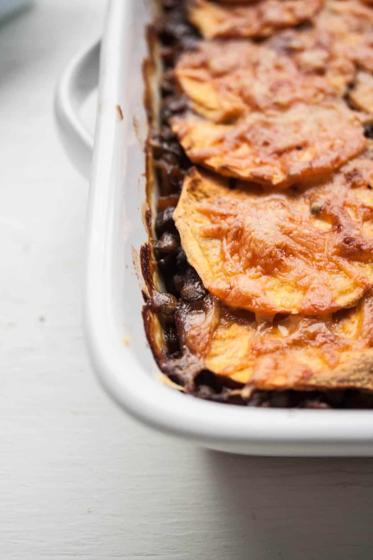 A close up of sweet potato lentil lasagne in a dish.