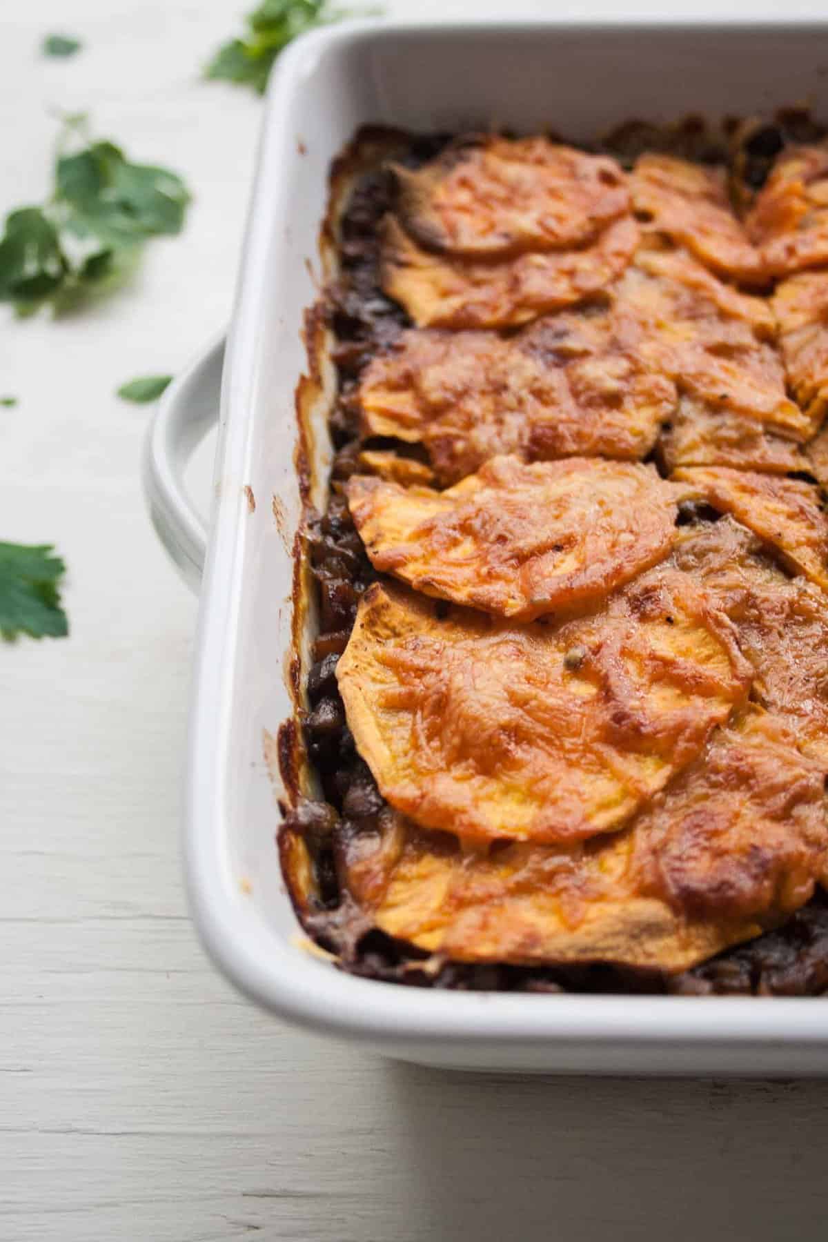 A close up of a lentil sweet potato lasagne in a dish.