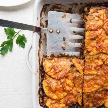 A spatula serving up sweet potato lentil lasagne slice from a dish.