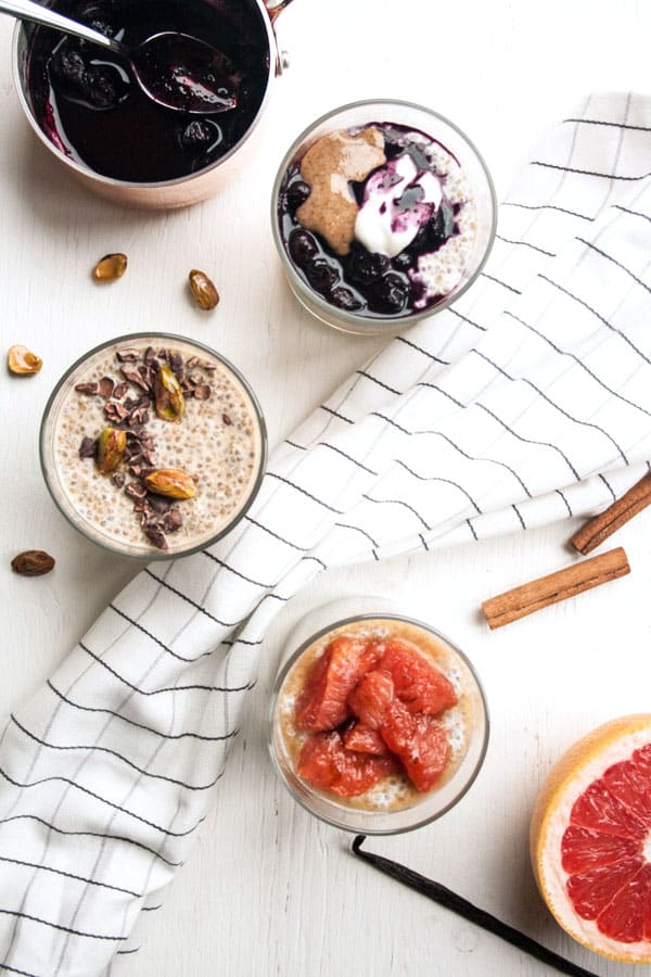 Three glasses with chia pudding and various toppings with a napkin running between.