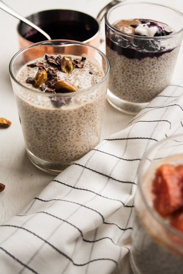 A glass of chia pudding with fruit on top with napkin in front.