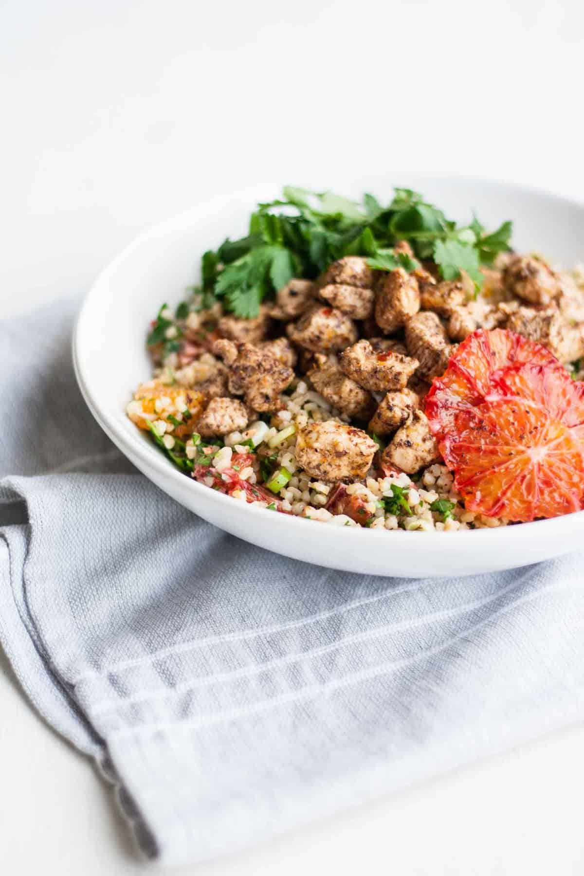 A bowl of chicken tabbouleh salad on a napkin.