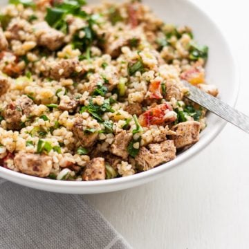 A messed up bowl of chicken tabbouleh with a fork.