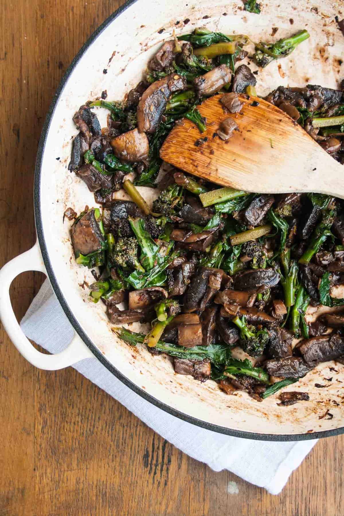 A skillet with mushroom ragu cooked inside and spatula.