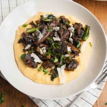 A plate of mushroom ragu served on top of polenta with a fork to the side.