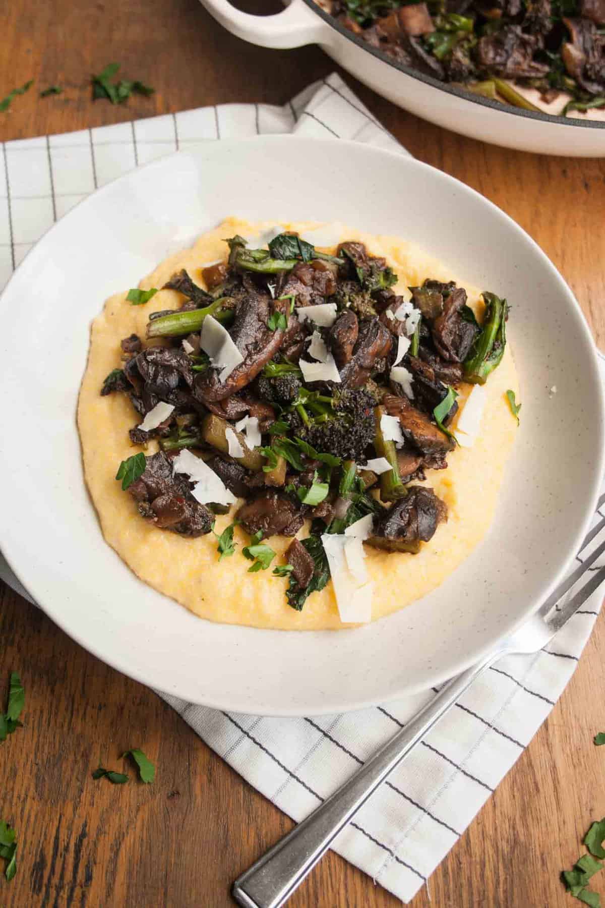 A plate of mushroom ragu served on top of polenta with a fork to the side.