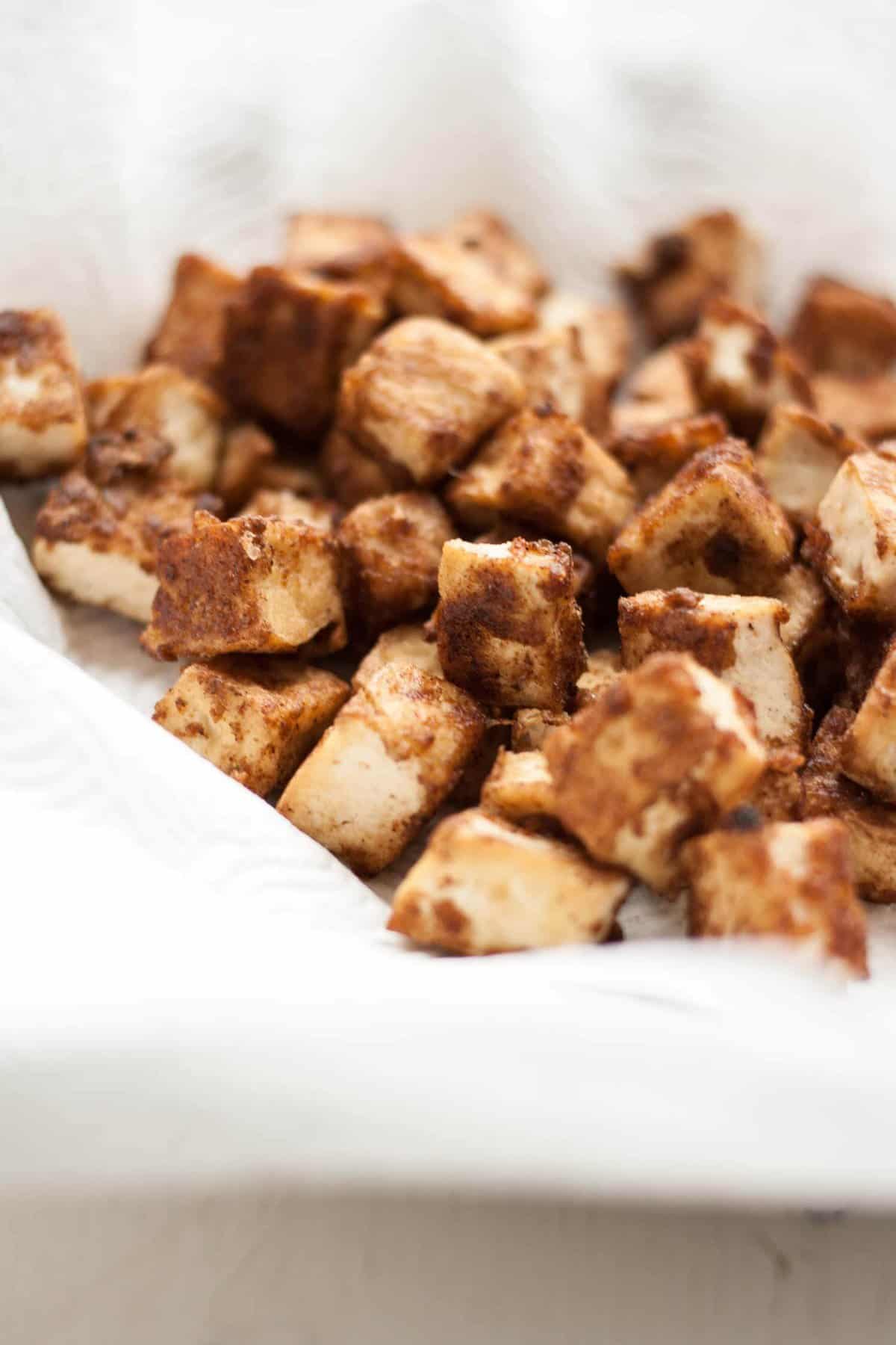 An array of crispy tofu draining on kitchen paper.