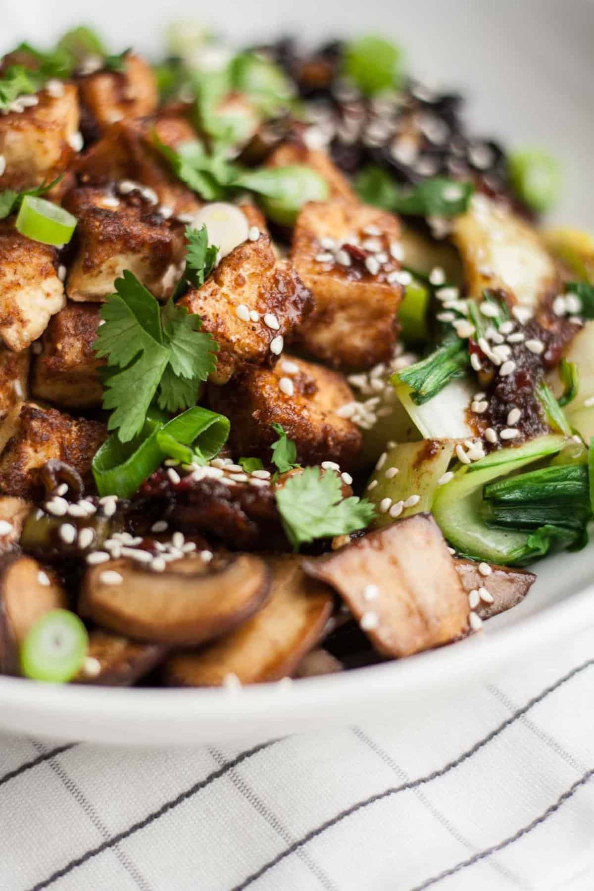 Close up of the crispy tofu in a bowl with mushrooms.