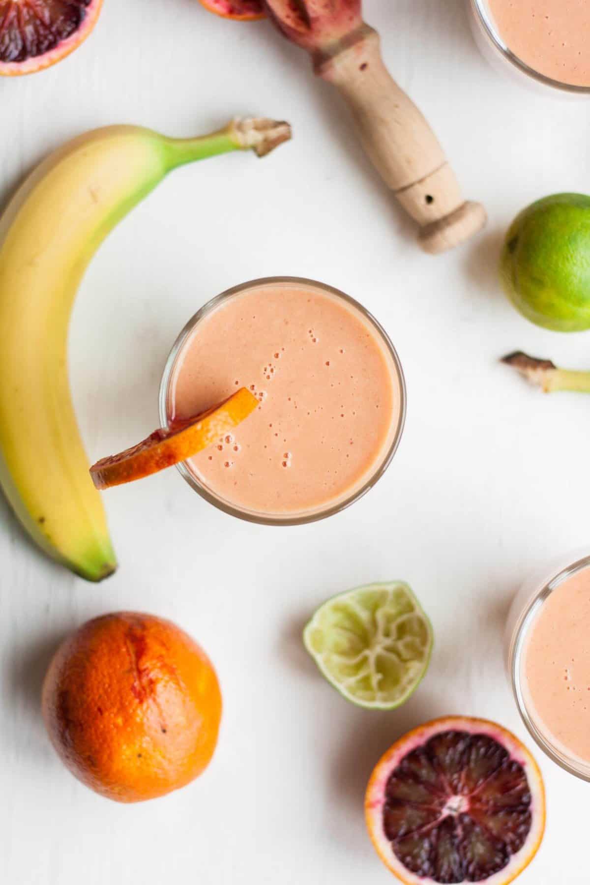 A glass of orange and mango smoothie with a slice of orange on edge of glass.