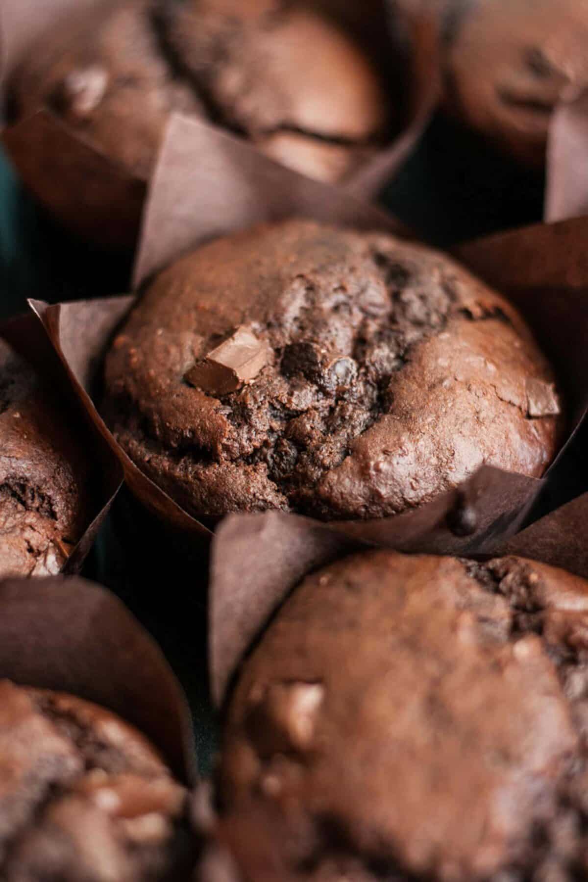 Close up of a chocolate muffin with chocolate chunks on top.