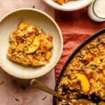 two bowls of peach baked oatmeal with a spoon in the baking dish having served up.