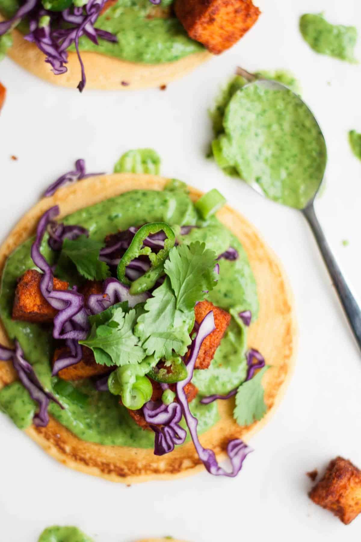 A socca pizza with avocado cream, sweet potato and salad on top.