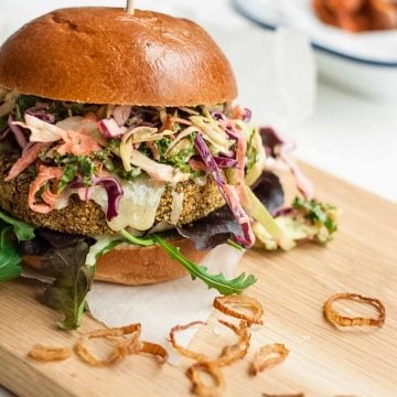 A veggies burger loaded with slaw on a wooden board.