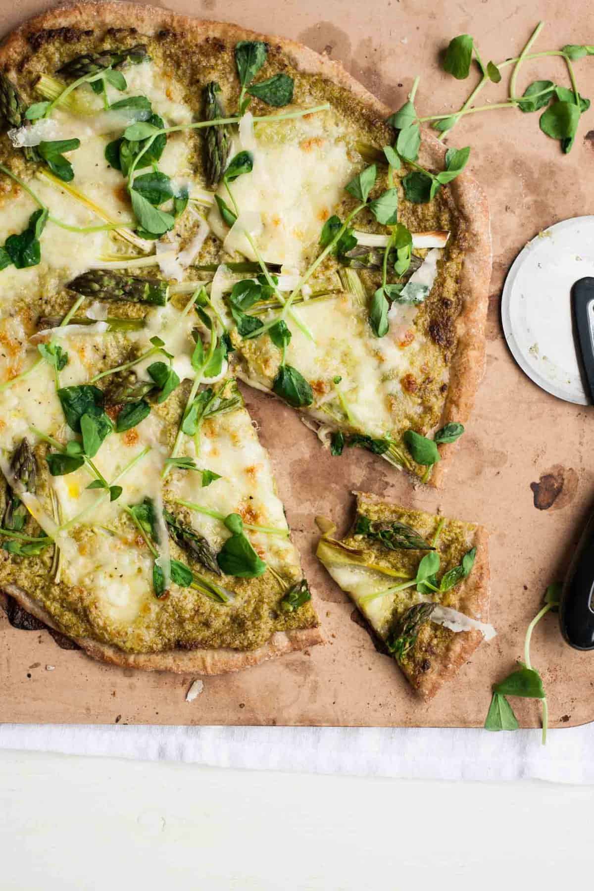 A pizza on a cooking stone with a wedge cut out of it.