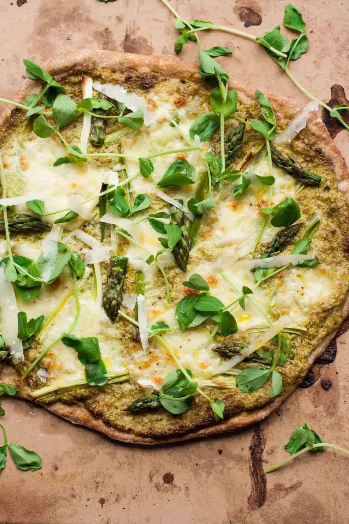 Asparagus pesto pizza topped with cheese and pea shoots.