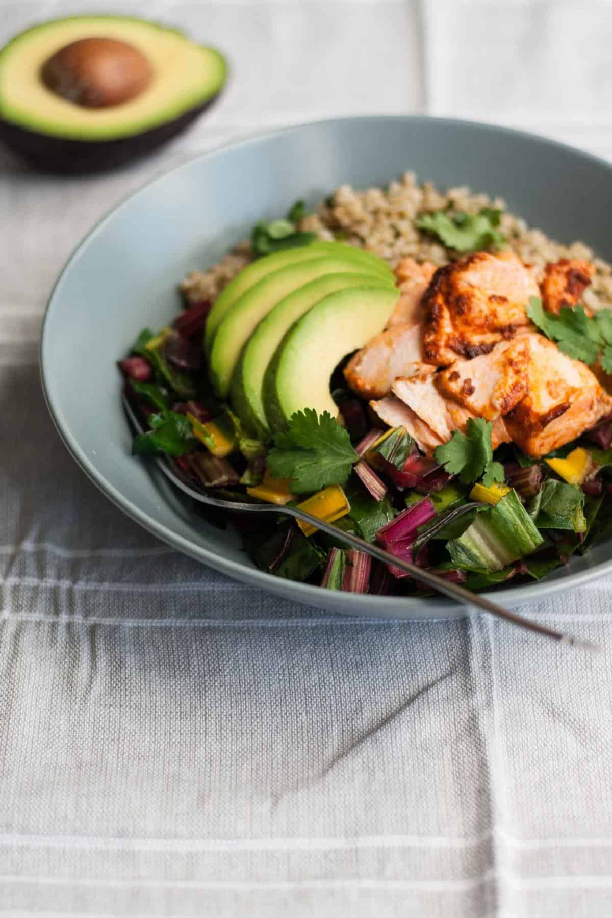 A close up of a fork in a salmon chard salad bowl.