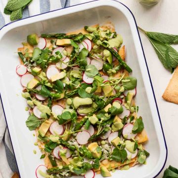 A tray with healthy asparagus nachos topped with avocado and pea shoots.