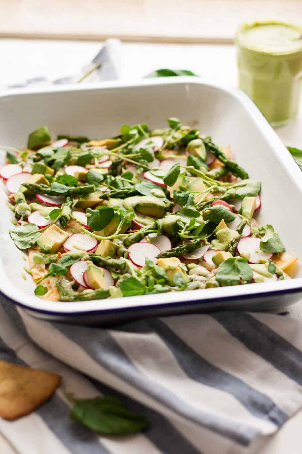 A tray with asparagus nachos and pea shoots on napkin.