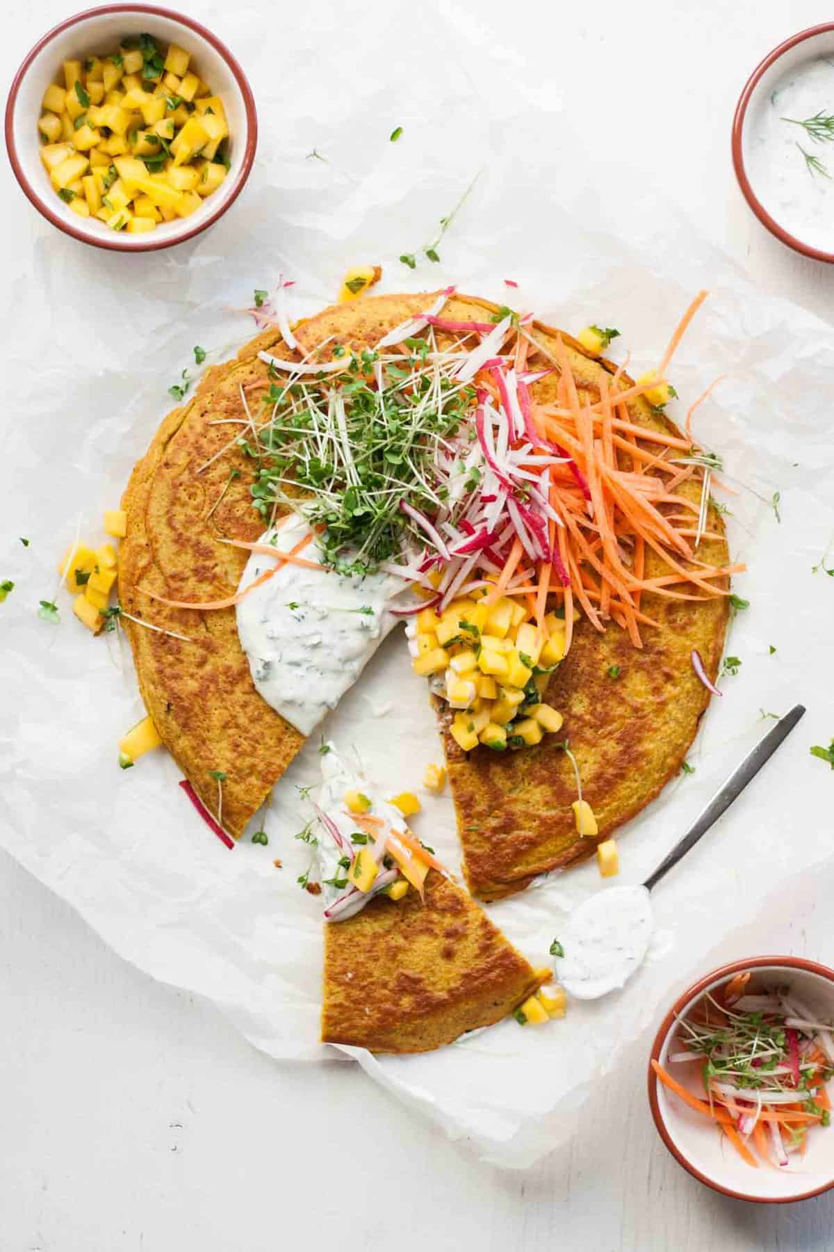 A wedge cut from the onion bhaji pancake with salad toppings and salsa.