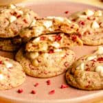 White chocolate raspberry cookies on a plate with one broken in half showing the insides.