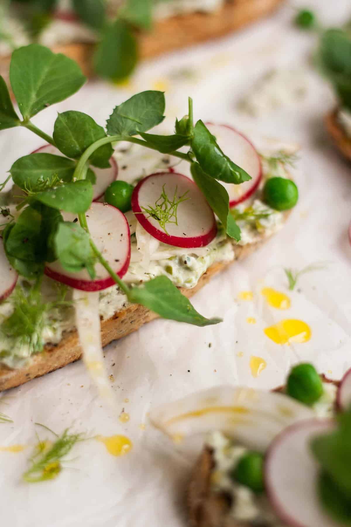 A crostini with radish and peashoots and oil.