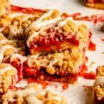 Strawberry crumble bars in a stack with brown butter glaze drizzled on top.