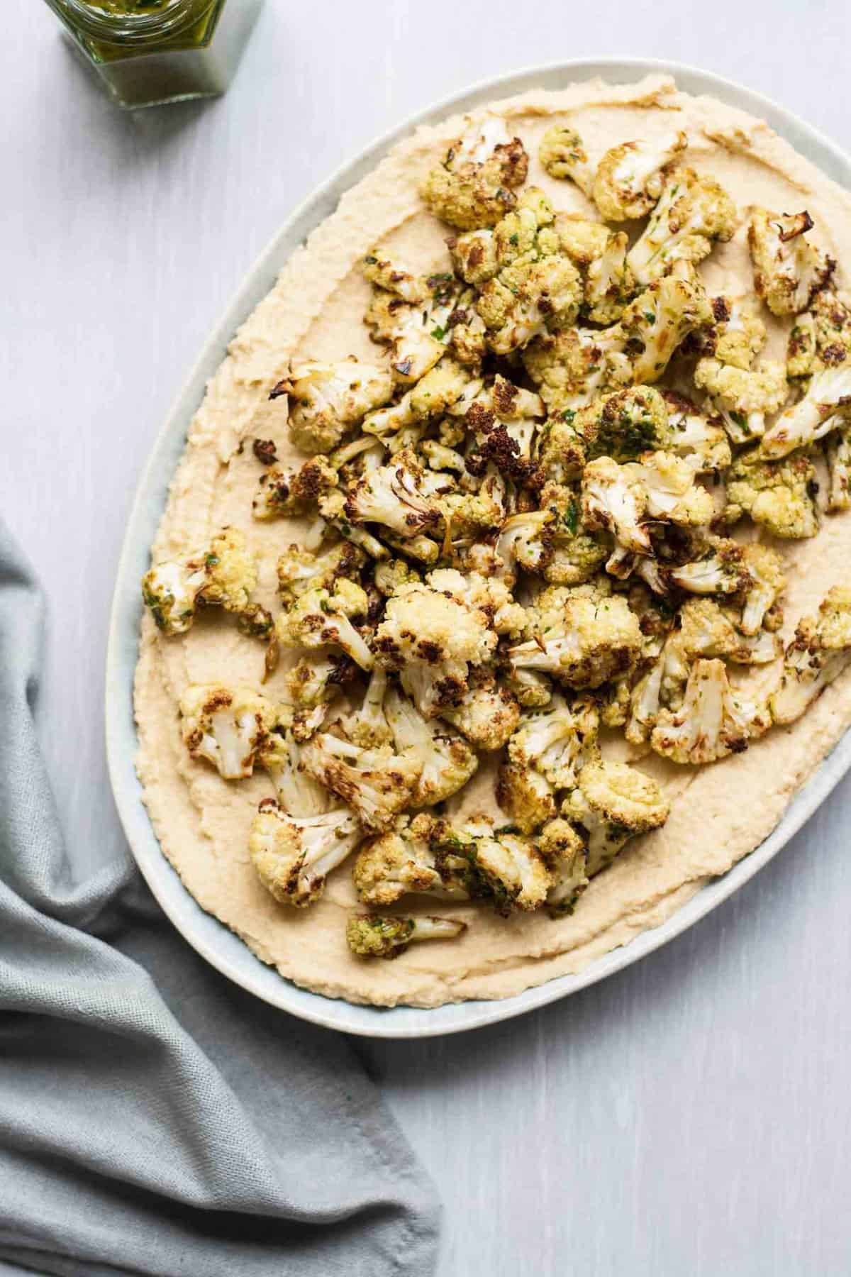 A plate of hummus topped with cauliflower and chimichurri.