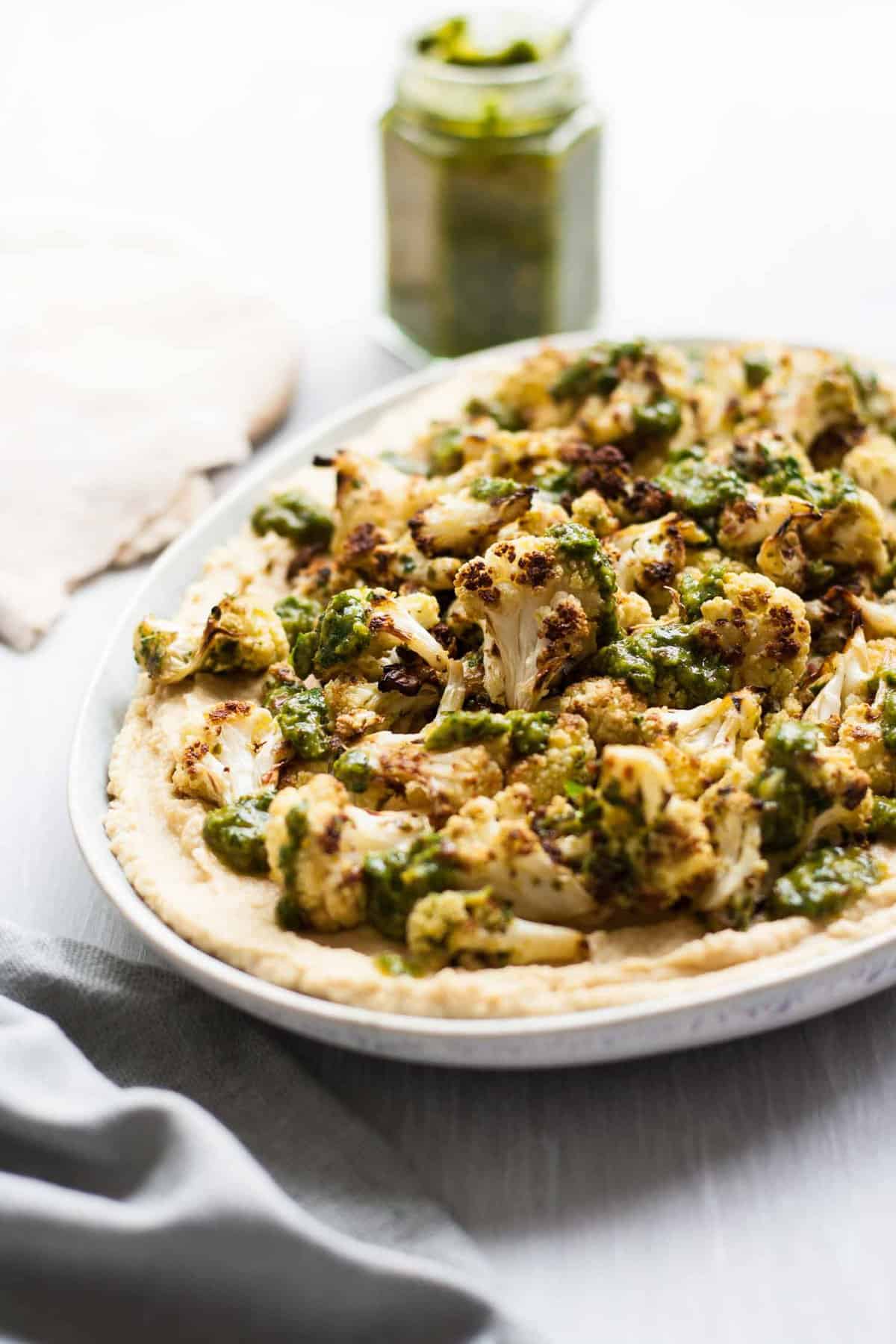 A close up of hummus topped with cauliflower and chimichurri.