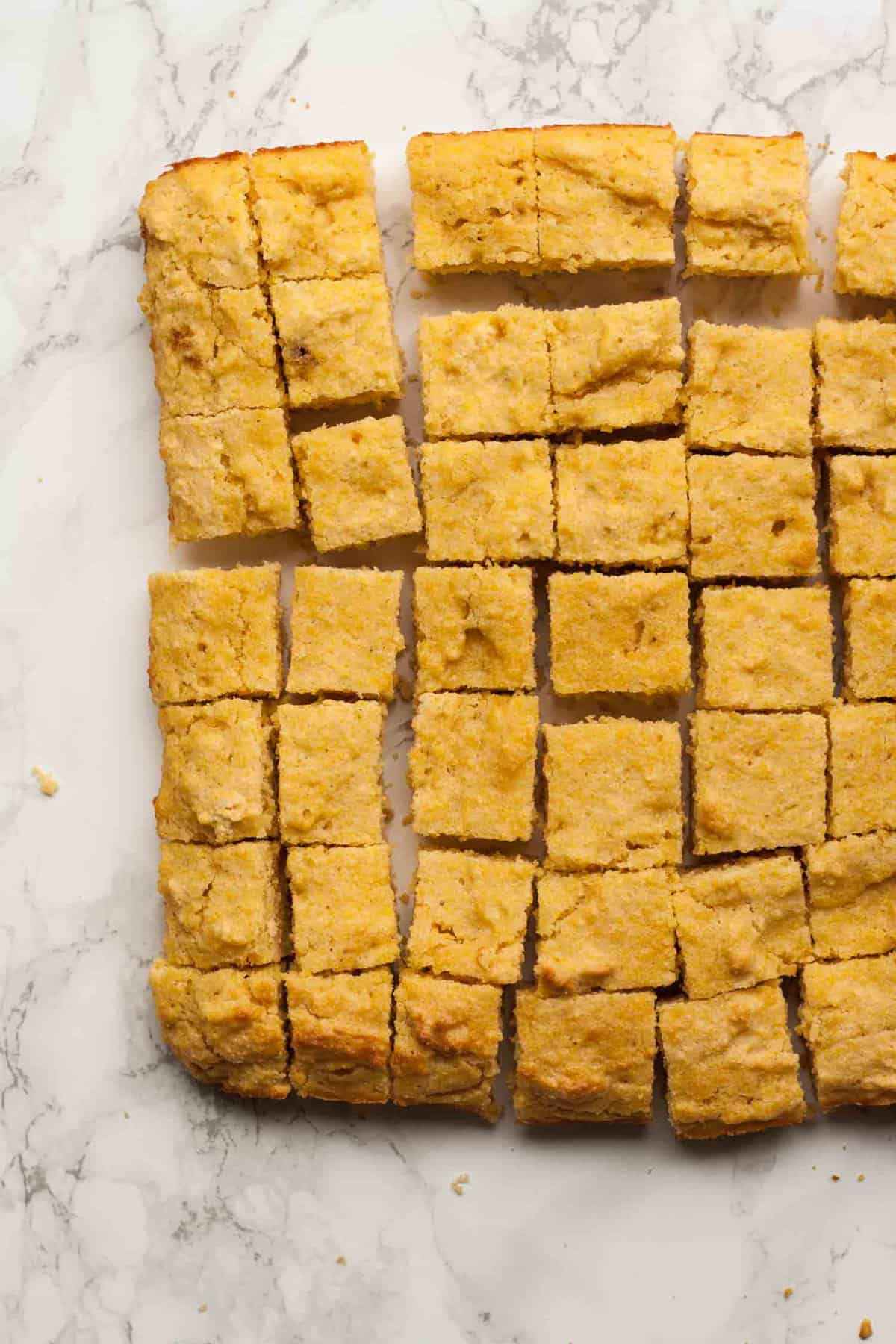 Cubed cornbread on a marble work top.