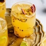 Passionfruit mocktail in a glass on a gold tray with passionfruit and lime slide on top.