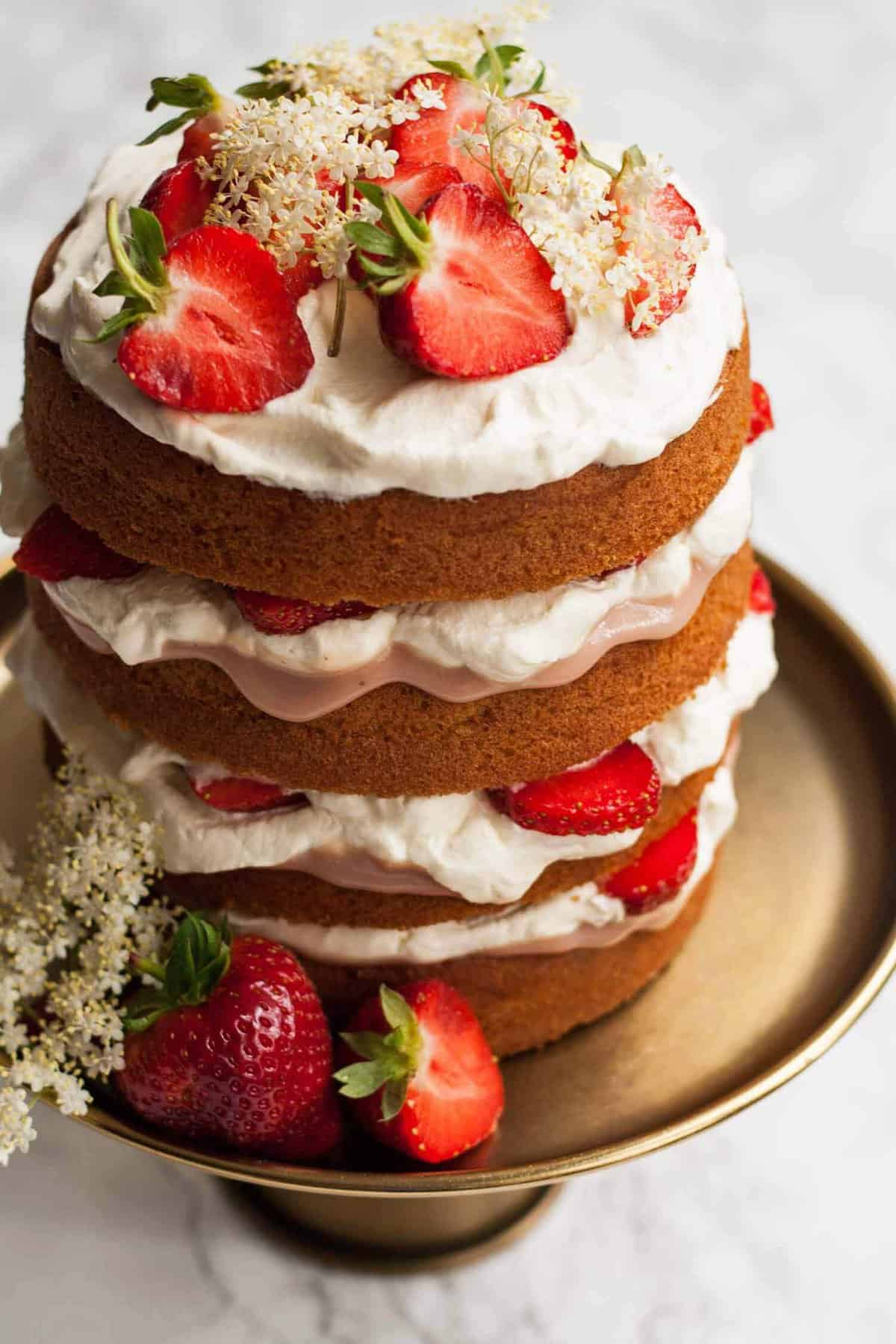 Side on shot of strawberry elderflower curd cake on a cake plate.