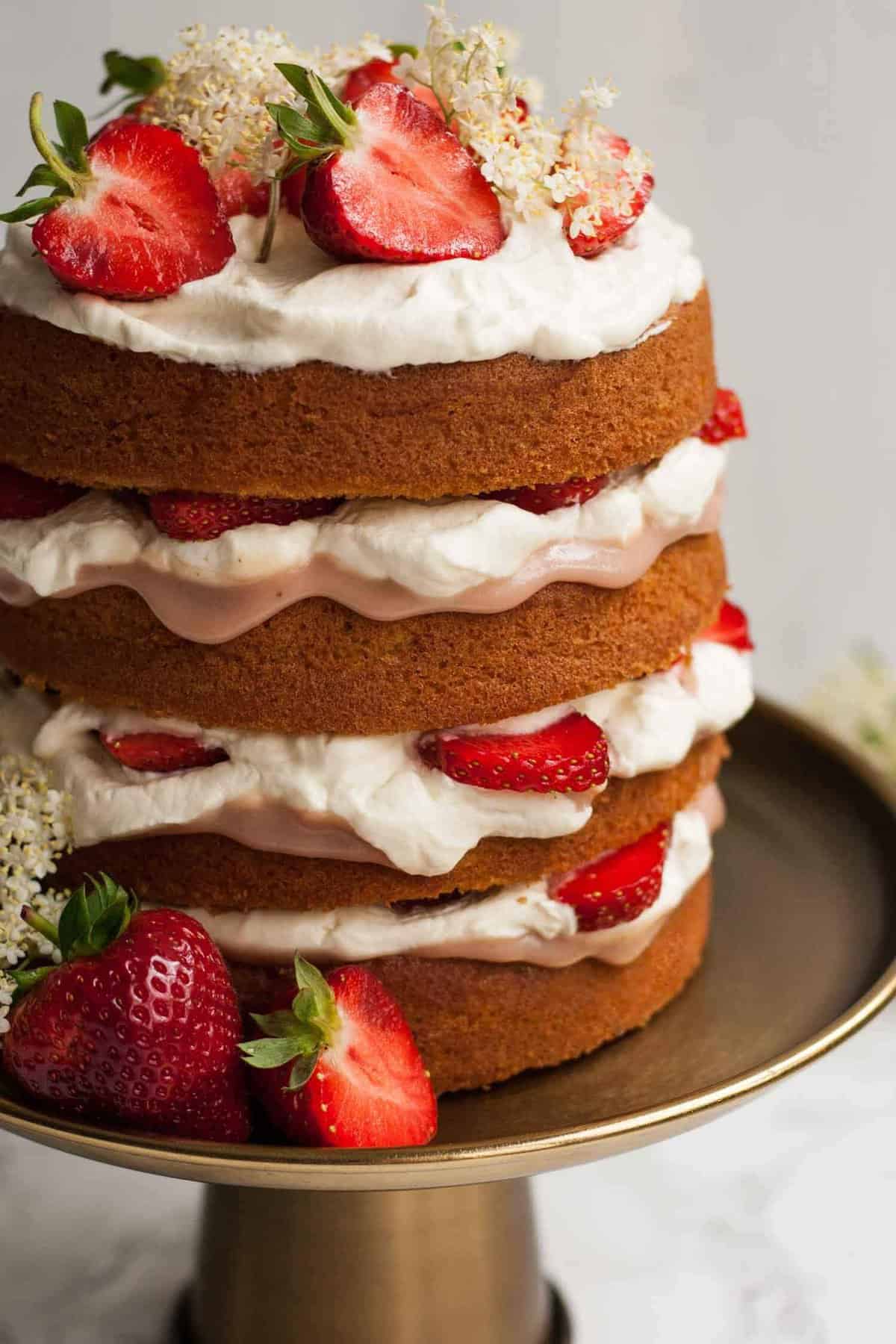 A side on of cake on a cake showing the layers with cream, curd and strawberries.