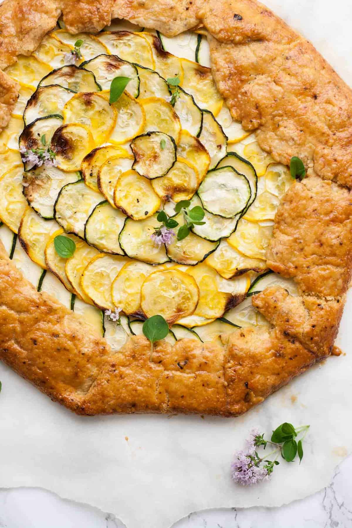 Close up of zucchini galette with fresh thyme flowers on top.